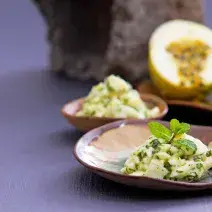 Foto da receita de salada de casca de maracujá, servida sobre um prato em formato de folha de árvore, numa bancada com um maracujá aberto ao fundo