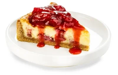 Fotografia em tons de vermelho em um fundo branco com um prato branco fundo ao centro com uma fatia da cheesecake de morango.