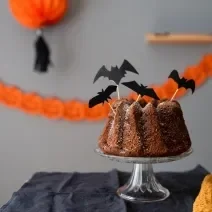 Fotografia de um bolo simples decorado com itens de dia das bruxas.