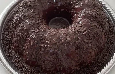 Foto em tons de marrom da receita de bolo cenourolate servida em uma porção grande sobre uma forma descartável branca Foto em tons de marrom da receita de bolo cenourolate servida em uma porção grande sobre uma forma descartável branca