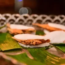 Foto da receita de Ginga com Tapioca. Observa-se algumas tapiocas recheadas de peixe empanado sobre folhas de bananeira.