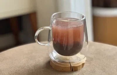 Foto da receita de Bubble Tea Caseiro, servido em uma xícara de vidro transparente, sobre uma pequena base de madeira em uma mesa Foto da receita de Bubble Tea Caseiro, servido em uma xícara de vidro transparente, sobre uma pequena base de madeira em uma mesa