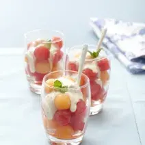 3 copos transparentes com bolinhas de melão e melancia com creme por cima