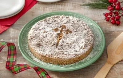 Foto da receita de torta de santiago servida em um prato verde grande sobre uma mesa de madeira com decoração de natal e uma espátula de madeira ao lado Foto da receita de torta de santiago servida em um prato verde grande sobre uma mesa de madeira com decoração de natal e uma espátula de madeira ao lado