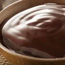 fotografia em tons de marrom tirada de um recipiente redondo com calda de chocolate dentro