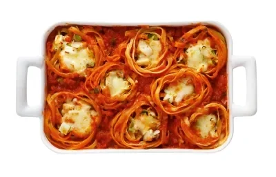 Foto de uma forma branca com 8 macarrão do tipo ninho dentro dela. Todos estão cobertos com molho de tomate e recheados com requeijão e queijo