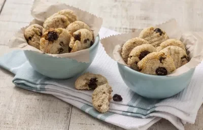 Fotografia em tons de branco e azul de uma bancada branca com um paninho azul e branco, sobre ele dois recipiente redondos azuis com biscoitinhos. Fotografia em tons de branco e azul de uma bancada branca com um paninho azul e branco, sobre ele dois recipiente redondos azuis com biscoitinhos.