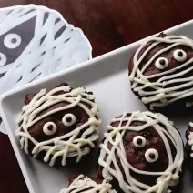 Fotografia de cookies de chocolates cobertos por fios de chocolate branco para imitar uma múmia.