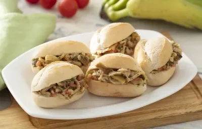 Foto da receita de casca louca de banana. Observa-se 5 pães franceses com casca louca de banana dentro em um prato branco grande. Foto da receita de casca louca de banana. Observa-se 5 pães franceses com casca louca de banana dentro em um prato branco grande.