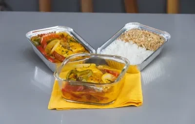 Foto da receita de Moqueca de Peixe Maggi, em um recipiente de vidro e alumínio, sobre um pano amarelo, em uma bancada Foto da receita de Moqueca de Peixe Maggi, em um recipiente de vidro e alumínio, sobre um pano amarelo, em uma bancada