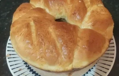 Foto da receita de pão de cebola em uma porção inteira servida sobre um prato de porcelana branco em cima de uma mesa de mármore