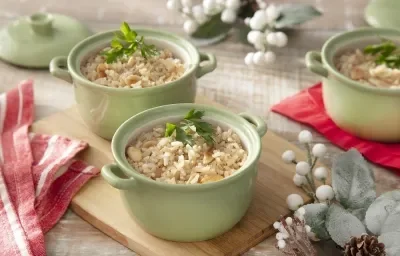 Foto da receita de arroz integral com amêndoas servida em três panelinhas verdes sobre uma tábua de madeira em cima de uma mesa decorada com elementos de inverno