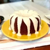 Fotografia em tons de amarelo com um prato amarelo ao centro. Em cima do prato existe um bolo de chocolate com cobetura de Ninho.