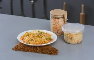 Foto da receita de salada de quinoa, servida em um prato branco, sobre uma tábua, e armazenada em potinhos de varios tamanhos