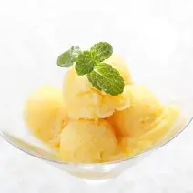 fotografia em tons de branco e amarelo tirada de um recipiente redondo com 4 bolas de sorvete