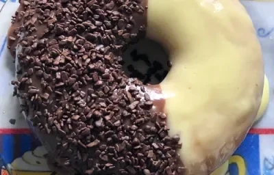 Foto da receita de Bolo Dois Amores. Observa-se um bolo visto de cima metade com branco e metade preto. A parte branca tem uma cobertura e a parte preta está coberta por granulado. Foto da receita de Bolo Dois Amores. Observa-se um bolo visto de cima metade com branco e metade preto. A parte branca tem uma cobertura e a parte preta está coberta por granulado.