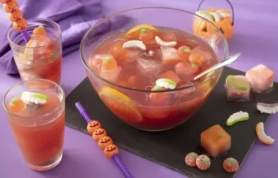 Foto da receita de ponche de halloween sem álcool servida em um recipiente de vidro grande com decoração de halloween em volta