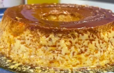 Foto da receita de pudim de leite moça na panela servida em uma porção grande sobre uma bancada cinza