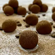 Foto da Receita de Trufa de Cappuccino. Observa-se 17 trufas dispostas sobre uma superfície com chocolate em pó polvilhado e decorada com grãos de café.
