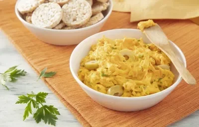 Foto da receita de Patê de Cenoura. Observa-se um potinho branco com o patê dentro e uma espátula de madeira sobre um pano laranja. Foto da receita de Patê de Cenoura. Observa-se um potinho branco com o patê dentro e uma espátula de madeira sobre um pano laranja.