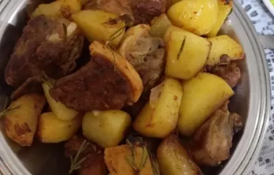 Foto da Receita de Costelinha de Porco com Batatas Salteadas no Alecrim. Observa-se um prato grande de servir de alumínio com as costelinhas e as batatas dispostas.