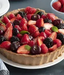 Imagem de uma torta em cima de um prato branco decorada com frutas vermelhas