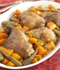 Imagem de uma travessa branco com pedaços de frango assado, quiabo e cenoura