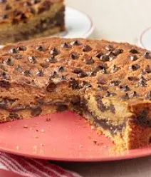 Imagem de uma torta cookie fatiada sobre um prato vermelho