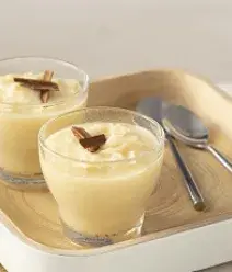 Imagem de dois copinhos de cocada sobre uma bandeja com duas colheres