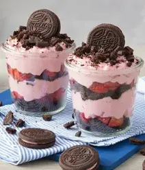 Imagem de 2 copos com um creme em camadas com morango e biscoito