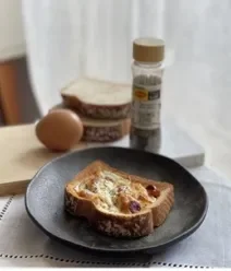 Receitas de Café da Manhã na Air Fryer Fotografia de um prato pouco fundo escuro pequeno, dentro tem pão e ovo dentro feito na air fryer.