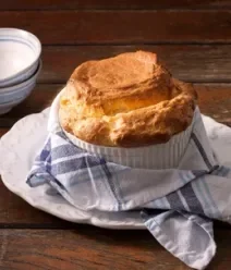 Fotografia mostra um sufle inflado e dourado em um ramequin branco Fotografia mostra um sufle inflado e dourado em um ramequin branco