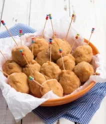 Fotografia mostra coxinhas espetadas com palitos coloridos em um cesto. Fotografia mostra coxinhas espetadas com palitos coloridos em um cesto.