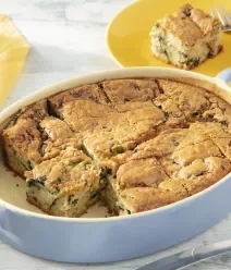 Receitas Para o Fim do Mês: Sem VR, Sem Crise Fotografia clara de uma forma de vidro oval azul com torta de legumes, om dois ou três pedaços cortados.
