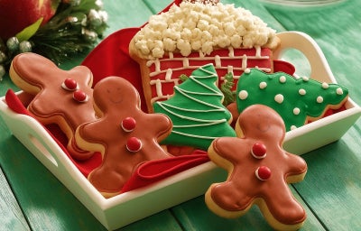 Bandeja com biscoitos de Natal decorados e coloridos em formato de casa, boneco e árvore.