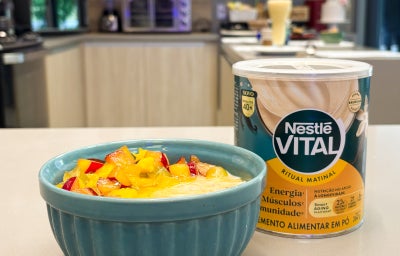 Fotografia em tons de verde e amarelo em uma bancada de cozinha, com um bowl e o mingau com frutas dentro