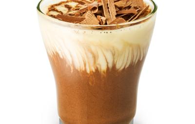 Fotografia em tons de marrom em uma fundo branco, um copo de vidro com a mousse de chocolate e outra mousse de baunilha dentro dele, misturando e formando uma mousse mesclada. Fotografia em tons de marrom em uma fundo branco, um copo de vidro com a mousse de chocolate e outra mousse de baunilha dentro dele, misturando e formando uma mousse mesclada.