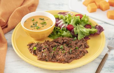 Foto da receita de Purê de Abóbora com Carne Desfiada. Observa-se um prato amarelo com a carne desfiada e a salada e, dentro de um potinho amarelo, o purê de abóbora finalizado com salsinha. Foto da receita de Purê de Abóbora com Carne Desfiada. Observa-se um prato amarelo com a carne desfiada e a salada e, dentro de um potinho amarelo, o purê de abóbora finalizado com salsinha.