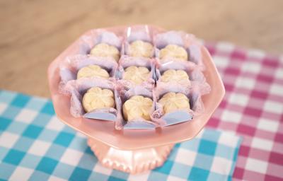 Fotografia de brigadeiros de leite ninho em formato de pétalas sobre forminhas azuis e rosa Fotografia de brigadeiros de leite ninho em formato de pétalas sobre forminhas azuis e rosa