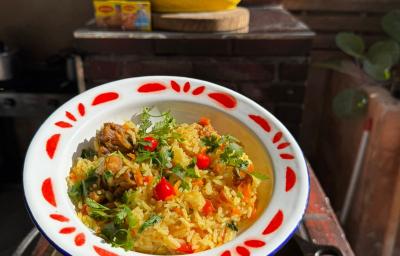 Fotografia mostra um prato com arrz amarelado, com pedaços de frango, cheiro-verde e pimenta biquinho.