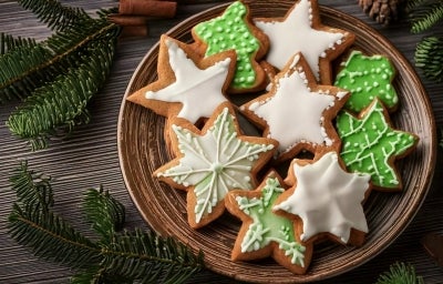 Em cima de uma mesa, prato redondo com porção de biscoitos em forma de estrela, decorados com glacê branco e verde. Em cima de uma mesa, prato redondo com porção de biscoitos em forma de estrela, decorados com glacê branco e verde.