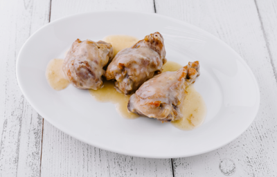 A imagem mostra cortes de frango assado com molho de vinho sobre um prato branco A imagem mostra cortes de frango assado com molho de vinho sobre um prato branco