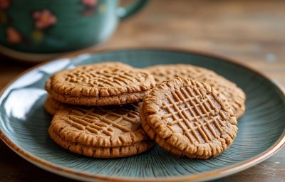 Em cima de uma mesa, prato redondo com biscoitos redondos, decorados com listas feitas com garfo.