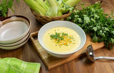 Fotografia em tons de verde com um pote branco ao centro. Dentro do pote existe uma receita de creme de milho. Fotografia em tons de verde com um pote branco ao centro. Dentro do pote existe uma receita de creme de milho.