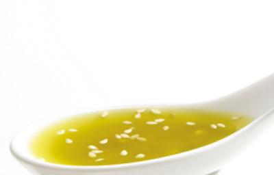 Fotografia em tons de amarelo em um fundo e mesa brancos com uma colher com o molho de mostarda com gergelim. Fotografia em tons de amarelo em um fundo e mesa brancos com uma colher com o molho de mostarda com gergelim.