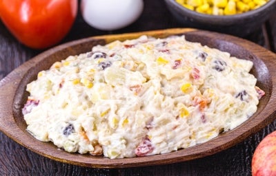 Fotografia de uma salada cremosa em uma tigela de madeira, com batatas, cenouras, ervilhas, uva-passa e milho, destacando a textura rica e ingredientes frescos, como um tomate e um ovo ao fundo, criando um ambiente rústico e acolhedor. Fotografia de uma salada cremosa em uma tigela de madeira, com batatas, cenouras, ervilhas, uva-passa e milho, destacando a textura rica e ingredientes frescos, como um tomate e um ovo ao fundo, criando um ambiente rústico e acolhedor.