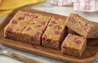 imagem mostra quadrados de brownie claro de milho e chocolate branco com pedaços de goiabada.