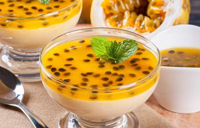 Foto da receita de Mousse de Maracujá Zero Lactose. Observa-se dois potinhos de vidro transparentes com a mousse de maracujá em cima, decoradas com as sementes da fruta. Foto da receita de Mousse de Maracujá Zero Lactose. Observa-se dois potinhos de vidro transparentes com a mousse de maracujá em cima, decoradas com as sementes da fruta.
