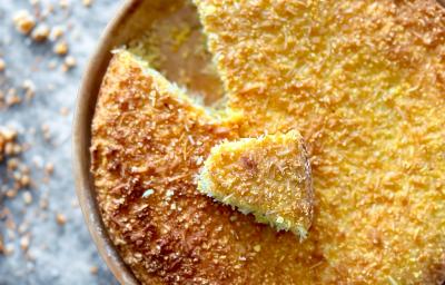 Fotografia mostra bolo de milho dourado, pedacinhos de coco visíveis na superfície. Fotografia mostra bolo de milho dourado, pedacinhos de coco visíveis na superfície.