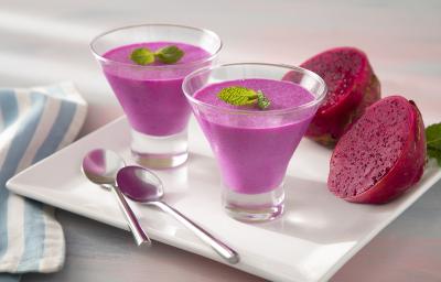 Foto da receita de Mousse de Pitaya e Leite Moça. Observa-se duas taças de vidro com a mousse cor-de-rosa decorada com hortelã em cima de um prato branco quadrado. Foto da receita de Mousse de Pitaya e Leite Moça. Observa-se duas taças de vidro com a mousse cor-de-rosa decorada com hortelã em cima de um prato branco quadrado.
